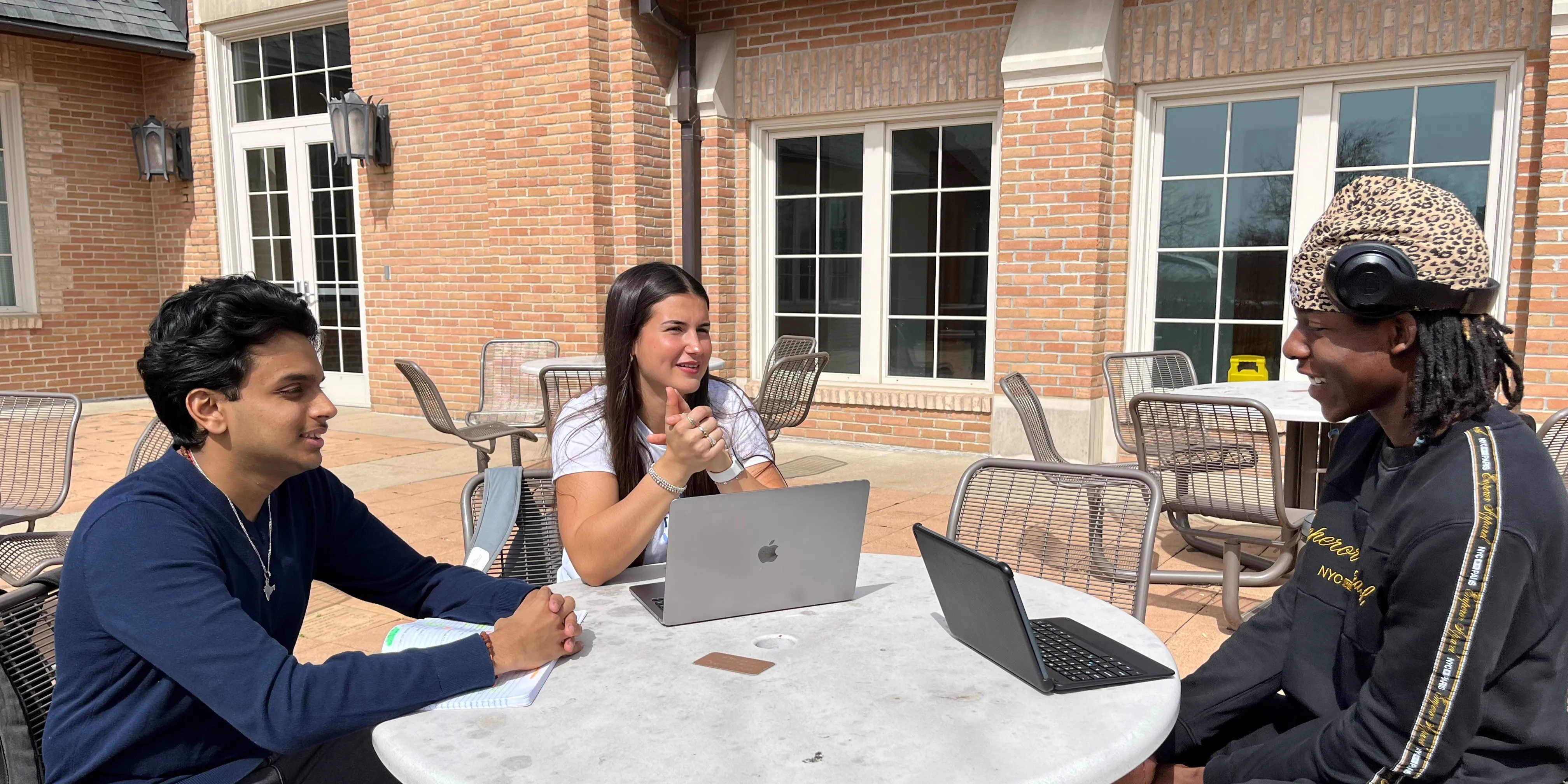 3 students sitting on a round table and chatting